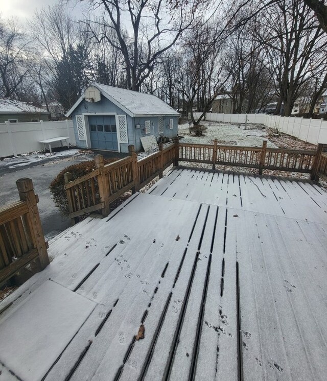 snow covered deck with an outbuilding and a garage