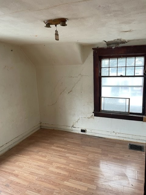 spare room featuring light hardwood / wood-style flooring and vaulted ceiling