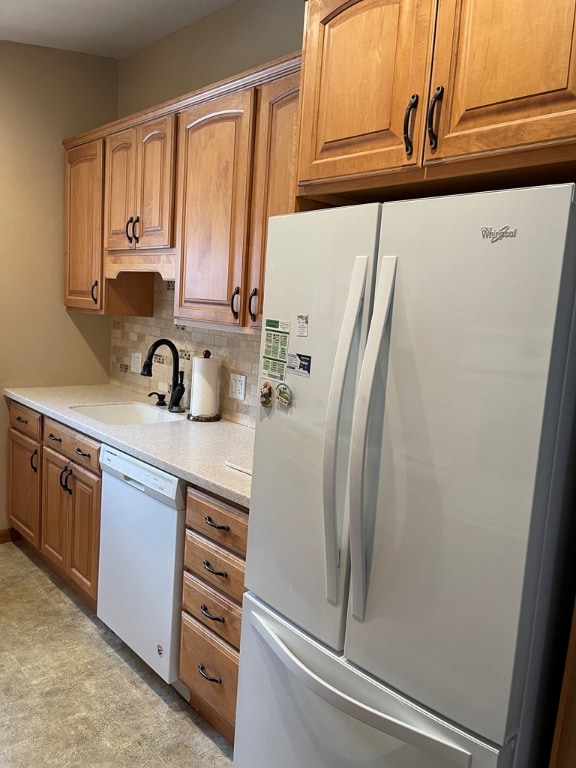 kitchen featuring light stone counters, white appliances, sink, and backsplash