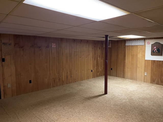 finished basement with carpet, wooden walls, and a drop ceiling