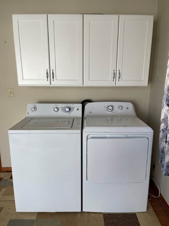 laundry area featuring washing machine and dryer, cabinet space, and baseboards