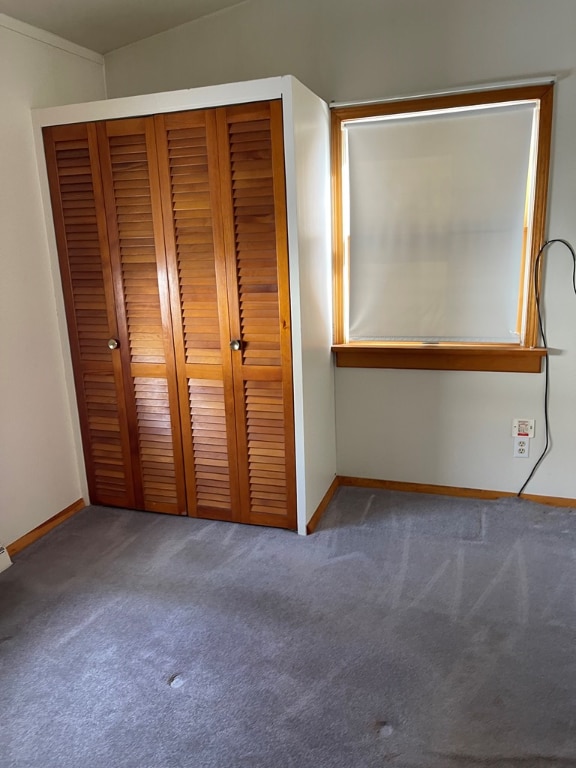 unfurnished bedroom with carpet, a closet, and baseboards