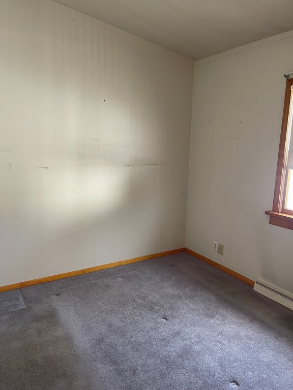 empty room featuring a baseboard radiator and carpet floors