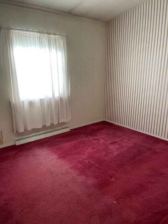 carpeted empty room with a baseboard radiator