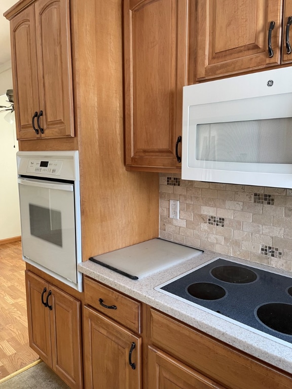 kitchen featuring ceiling fan, white appliances, light stone counters, and decorative backsplash