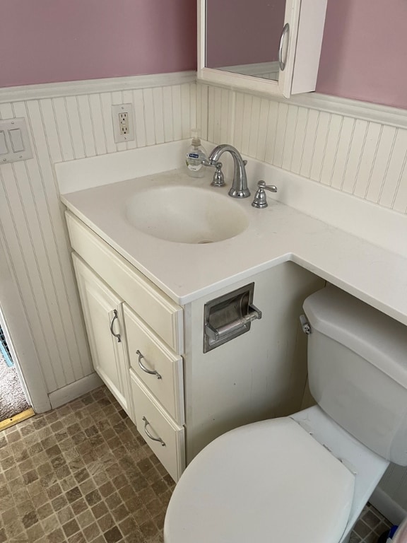 bathroom with toilet, vanity, and wainscoting