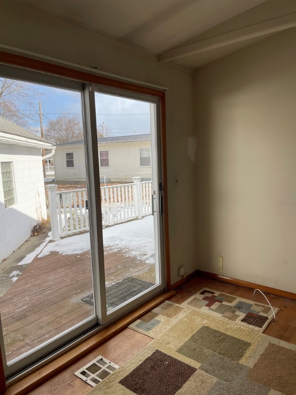 doorway to outside featuring visible vents, beamed ceiling, and baseboards