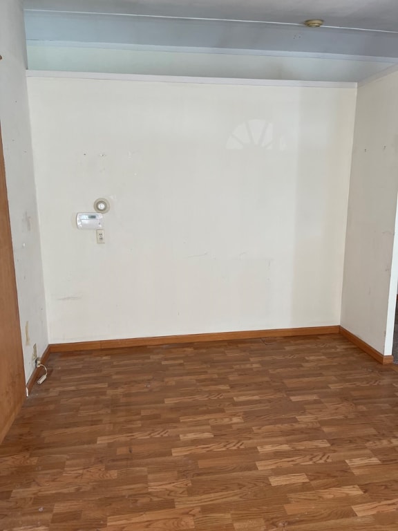 unfurnished room featuring dark hardwood / wood-style floors and beam ceiling