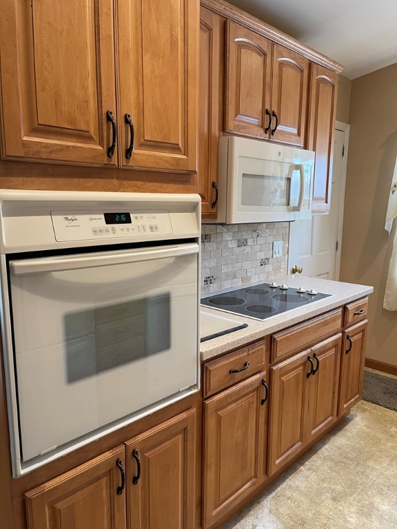 kitchen with light countertops, white appliances, backsplash, and brown cabinets