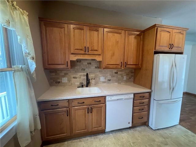 kitchen with brown cabinets, light countertops, backsplash, a sink, and white appliances