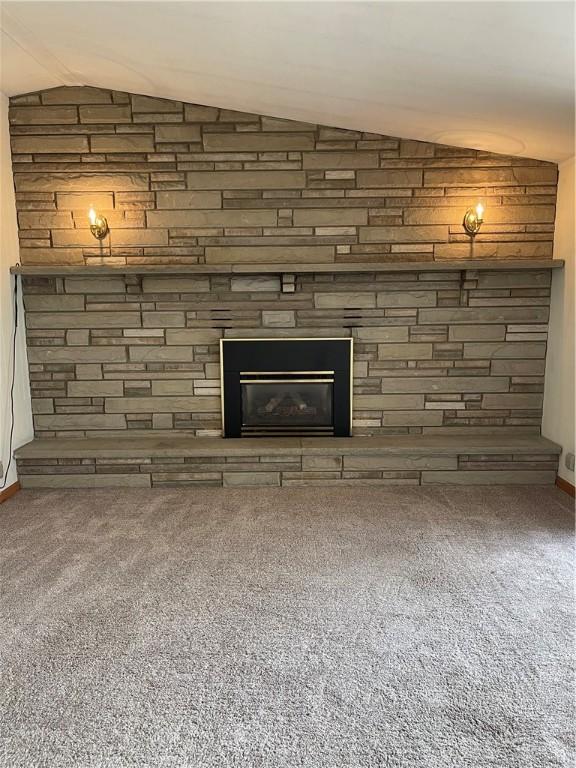 interior details featuring carpet floors and a stone fireplace