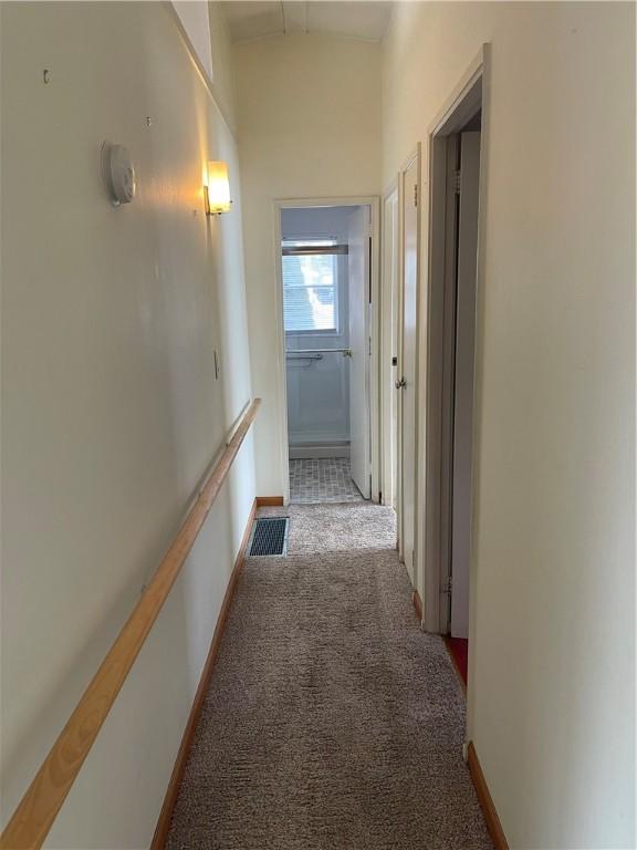 hall with carpet, visible vents, and baseboards