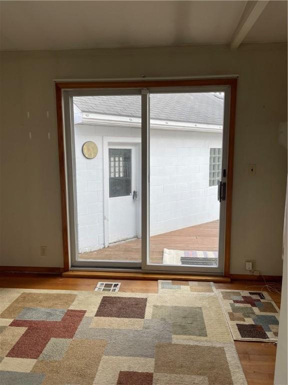 entryway featuring baseboards, beam ceiling, visible vents, and wood finished floors