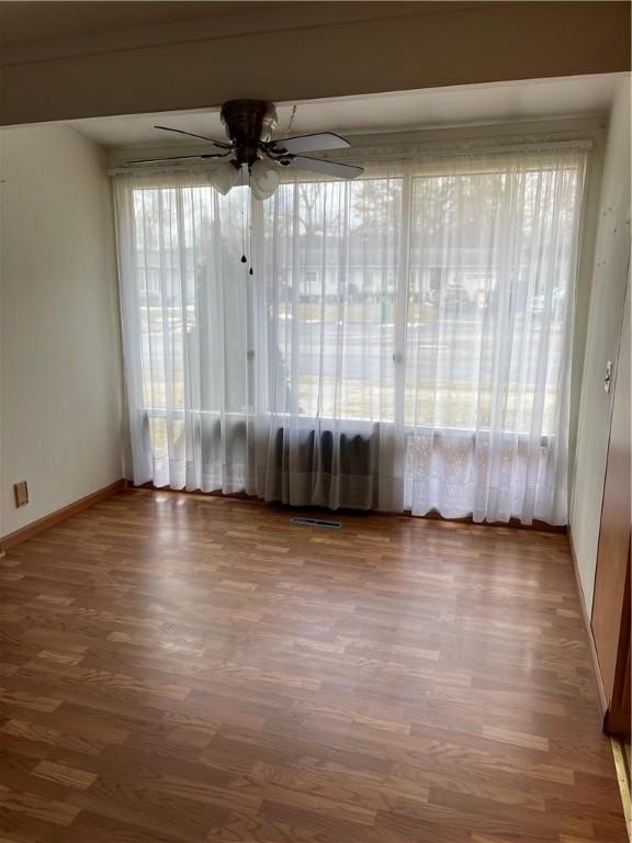 spare room featuring baseboards, a ceiling fan, and wood finished floors