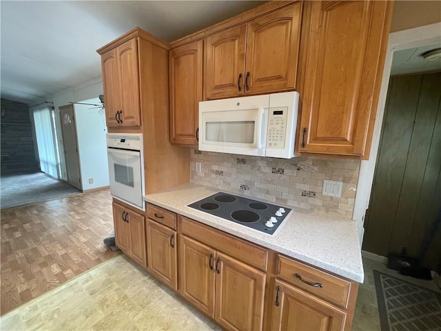 kitchen with white appliances, tasteful backsplash, light countertops, and brown cabinetry