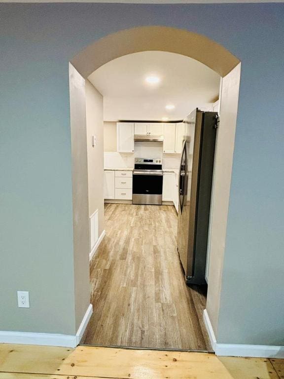 kitchen with stainless steel appliances, white cabinets, and light wood-type flooring