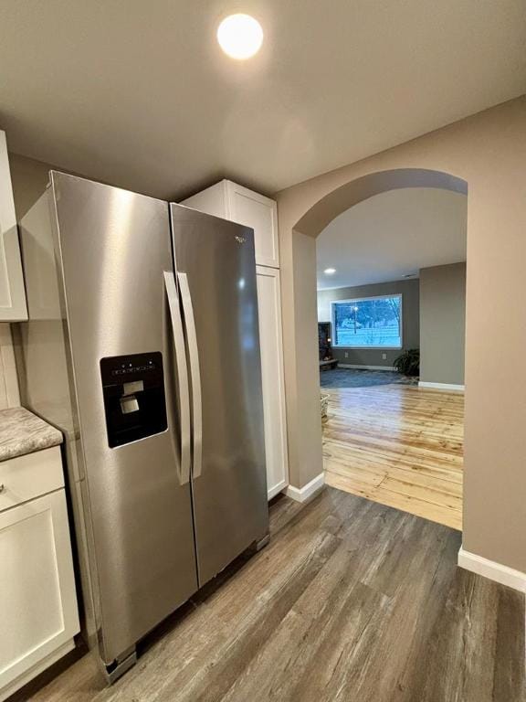 kitchen with white cabinets, hardwood / wood-style floors, and stainless steel fridge