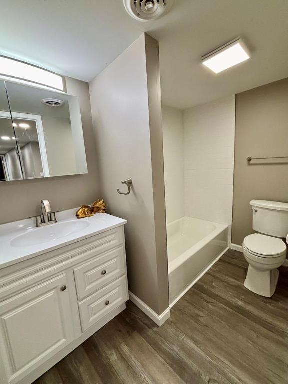 full bathroom featuring vanity, hardwood / wood-style flooring, shower / washtub combination, and toilet