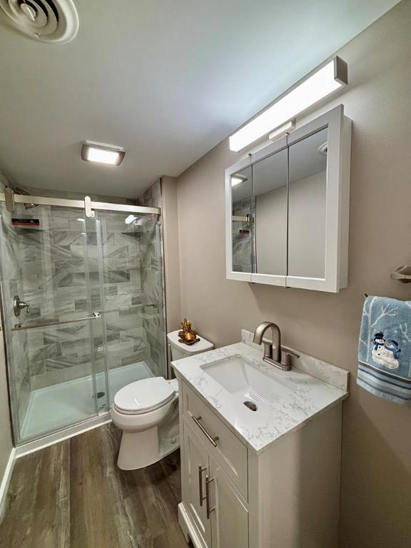 bathroom featuring vanity, toilet, a shower with door, and hardwood / wood-style floors