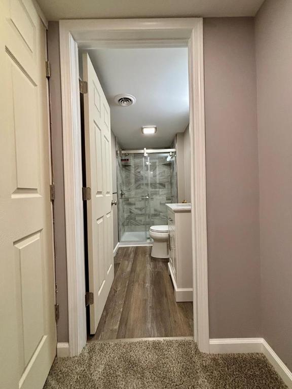 bathroom featuring wood-type flooring, toilet, and walk in shower