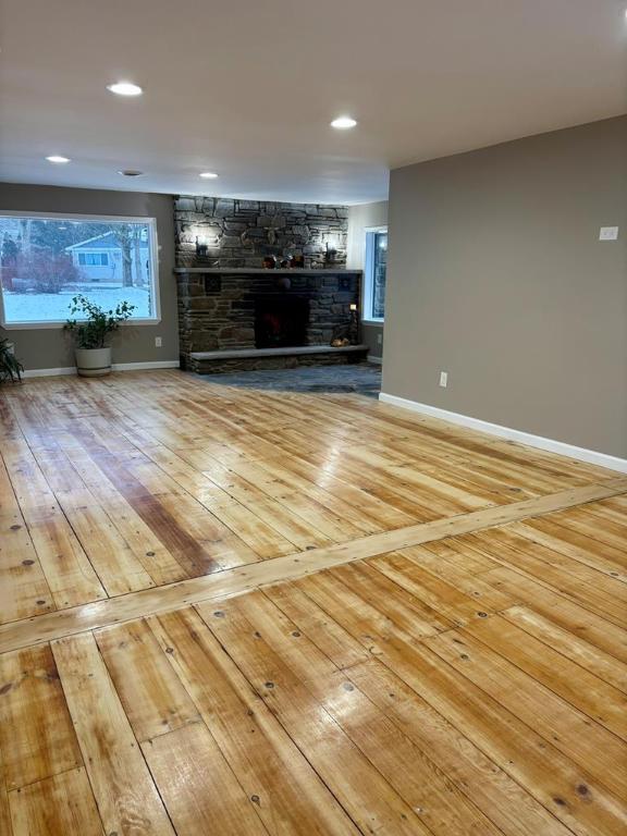 unfurnished living room featuring a stone fireplace and hardwood / wood-style floors