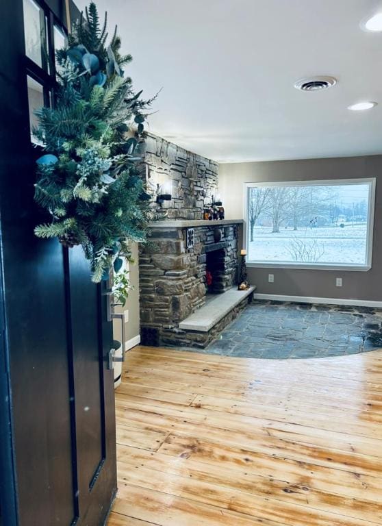 bar with a stone fireplace and light hardwood / wood-style floors