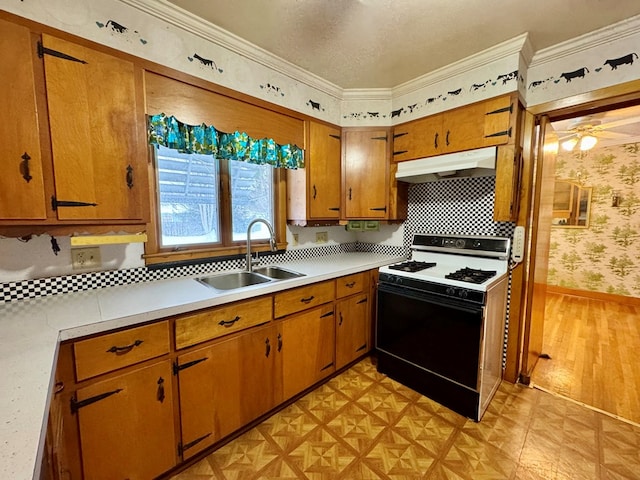 kitchen featuring light hardwood / wood-style flooring, range with gas stovetop, a textured ceiling, crown molding, and sink