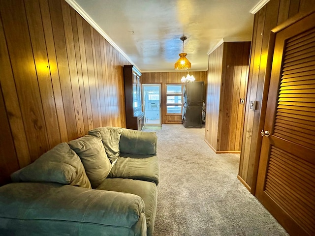 living room with wood walls, ornamental molding, light carpet, and a notable chandelier