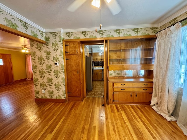 unfurnished dining area featuring ornamental molding, ceiling fan, and light hardwood / wood-style floors