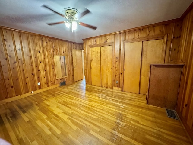 unfurnished room featuring ceiling fan, light hardwood / wood-style floors, crown molding, and wooden walls