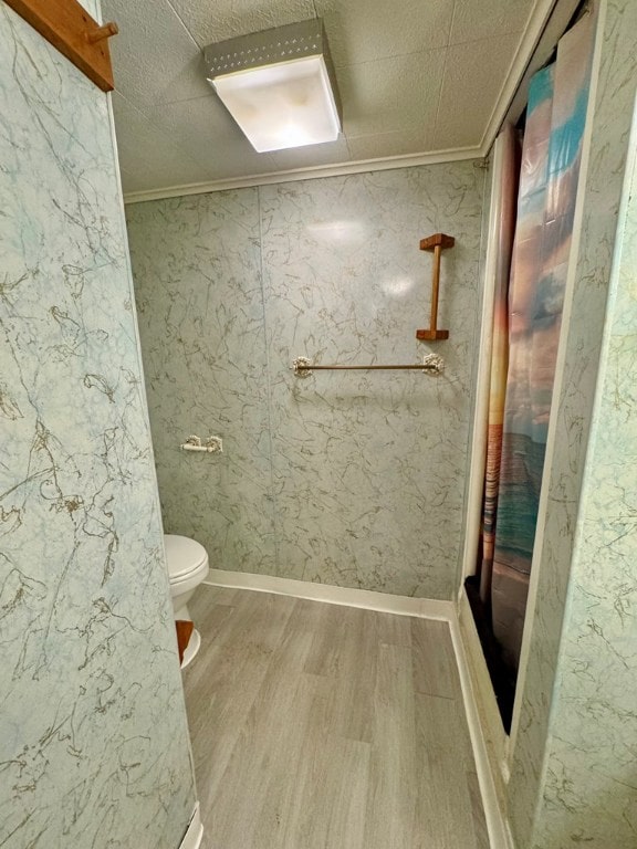 bathroom with toilet, hardwood / wood-style flooring, walk in shower, and crown molding