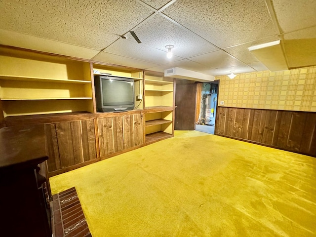 basement featuring gas water heater, carpet flooring, wood walls, and a paneled ceiling