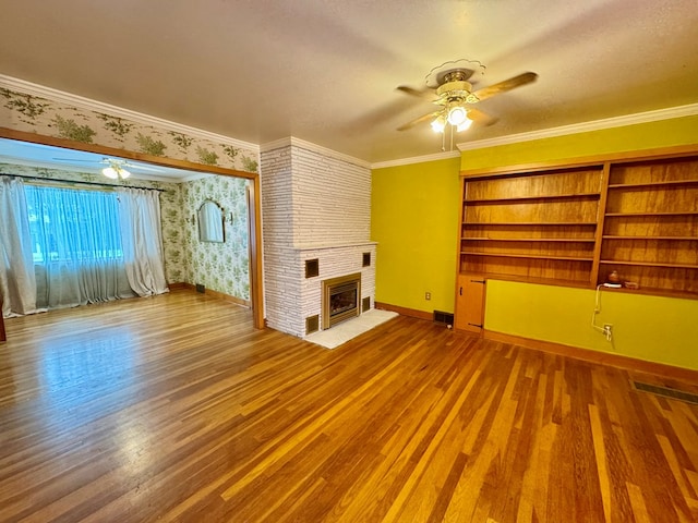 unfurnished living room featuring wood-type flooring, ceiling fan, crown molding, and a fireplace