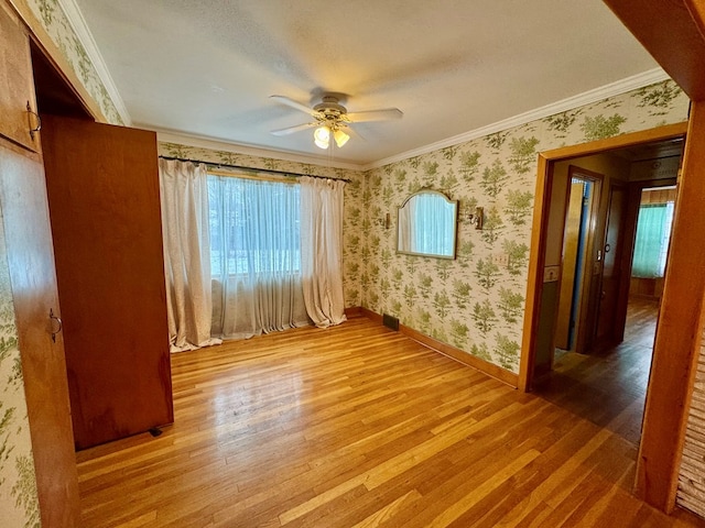 empty room featuring ornamental molding, light hardwood / wood-style flooring, and ceiling fan