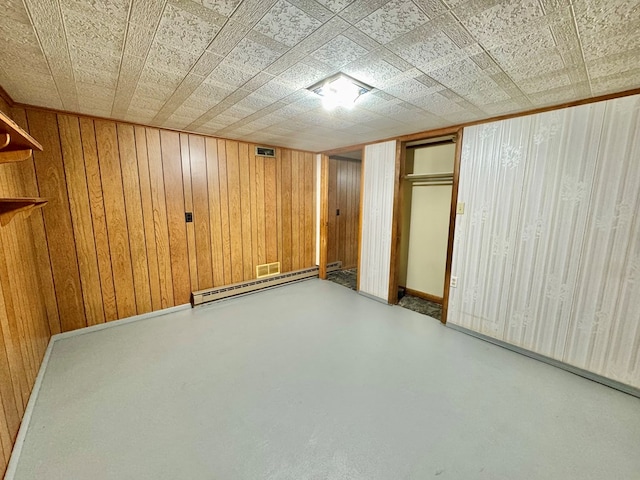 basement featuring wood walls and a baseboard radiator