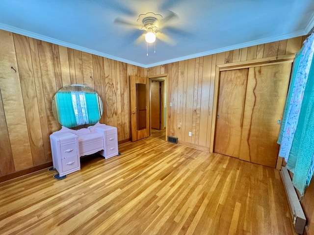 unfurnished bedroom with a baseboard radiator, a closet, ceiling fan, ornamental molding, and light wood-type flooring