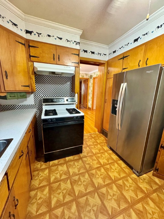 kitchen with crown molding, backsplash, light parquet flooring, stainless steel fridge with ice dispenser, and range with gas cooktop