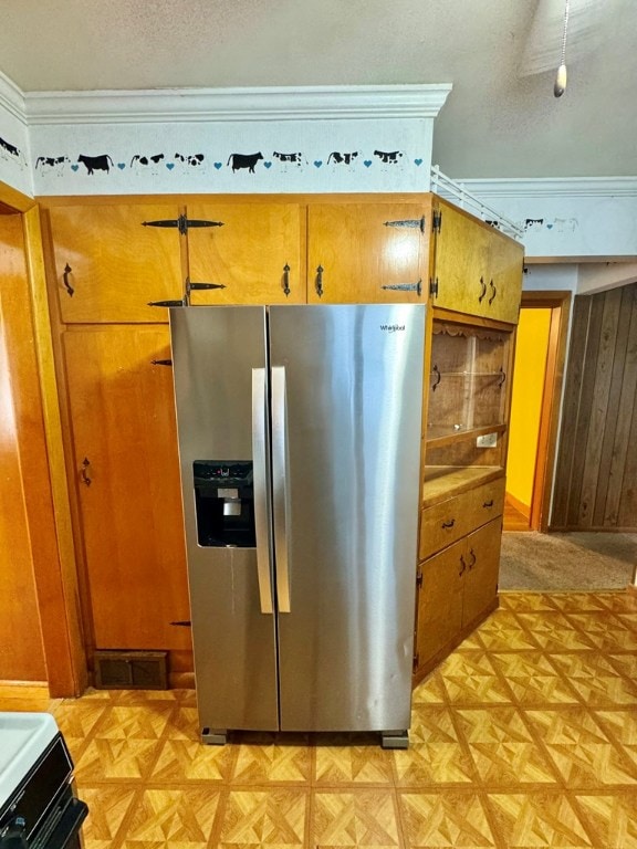 kitchen with a textured ceiling, stainless steel fridge with ice dispenser, wooden walls, light parquet floors, and ornamental molding