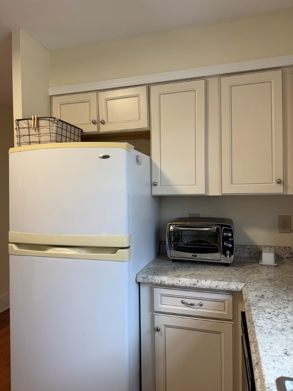 kitchen with light stone counters and white fridge