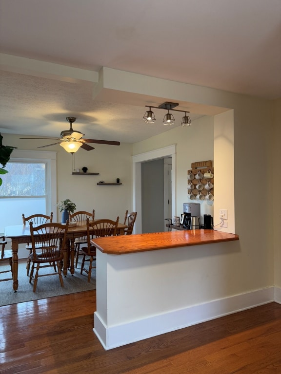 kitchen with dark wood-type flooring, ceiling fan, and kitchen peninsula