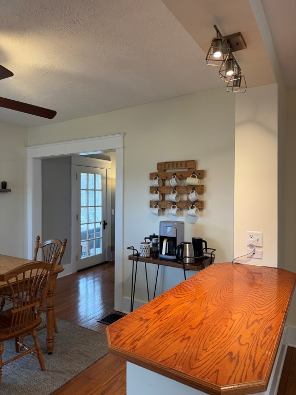 dining space featuring dark wood-type flooring, ceiling fan, and a textured ceiling