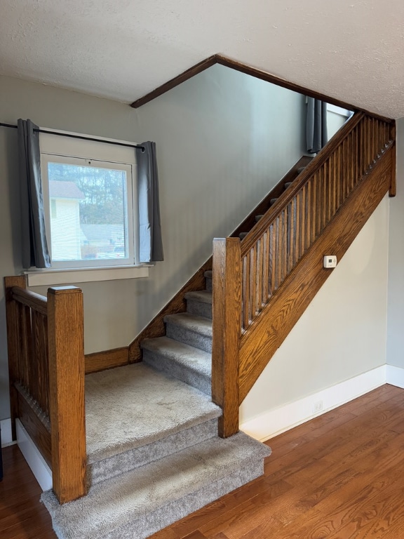 stairway with hardwood / wood-style flooring and a textured ceiling