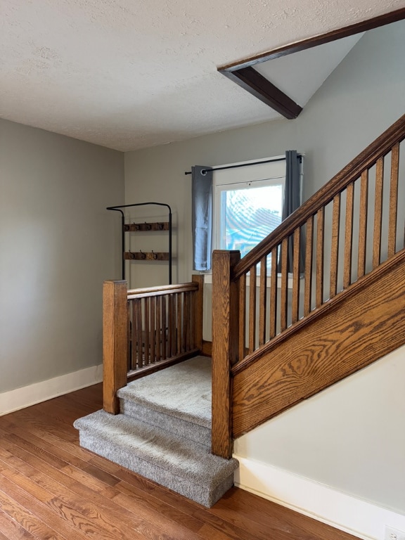 stairway with hardwood / wood-style floors and a textured ceiling