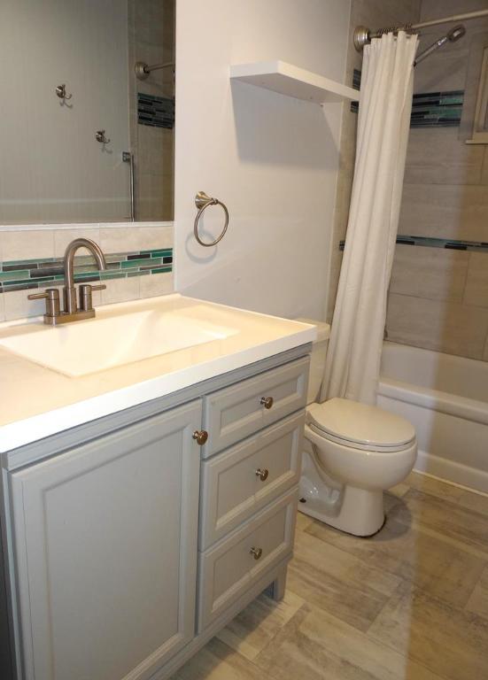 full bathroom featuring vanity, toilet, backsplash, and shower / bath combo with shower curtain