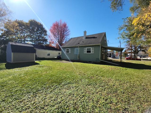 back of house with a carport, a shed, and a lawn