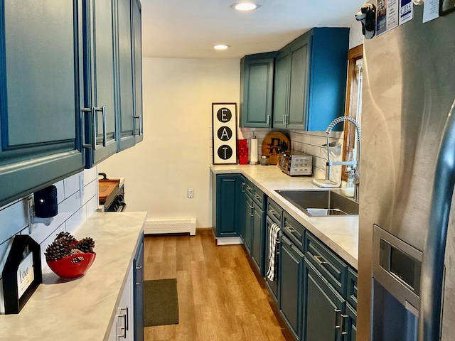 kitchen featuring decorative backsplash, stainless steel fridge, sink, and light hardwood / wood-style flooring