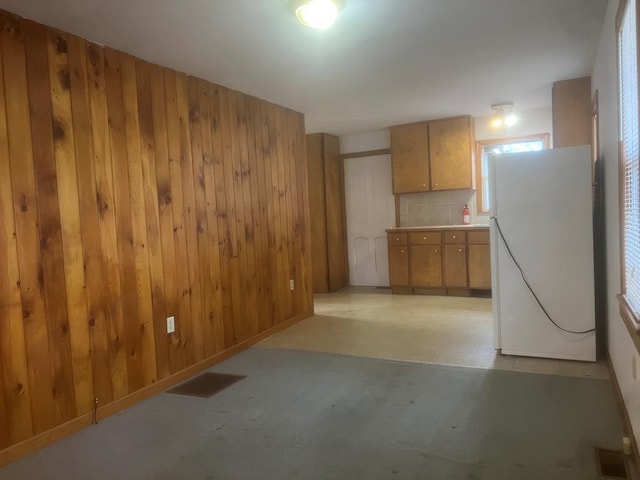 kitchen with decorative backsplash, wood walls, and white refrigerator