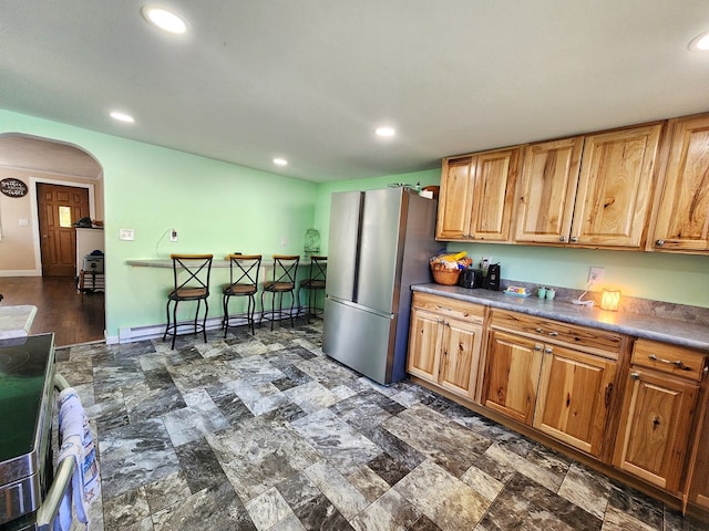 kitchen featuring stove, stainless steel refrigerator, and baseboard heating