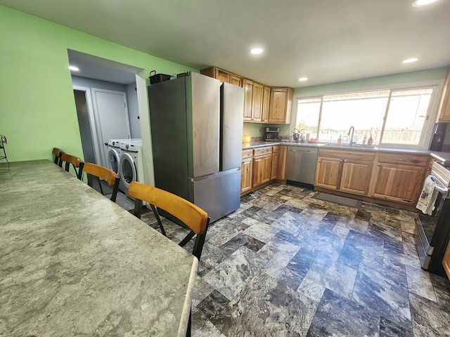 kitchen featuring independent washer and dryer, stainless steel appliances, and sink