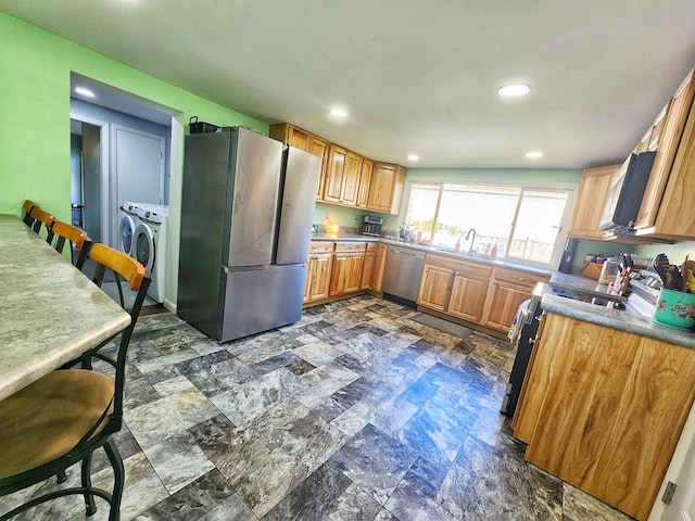 kitchen featuring washing machine and clothes dryer, stainless steel appliances, and sink